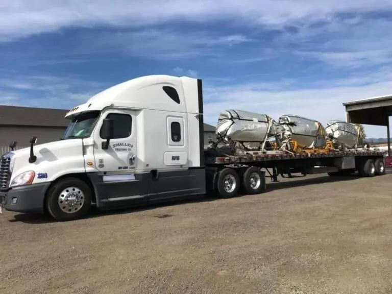 White semi-truck hauling cargo on flatbed.